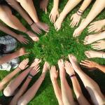 Dans l'herbe, un groupe de personnes posent leurs mains et pieds en cercle