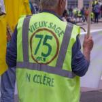 Gros plan sur un manifestant de dos portant un gilet jaune